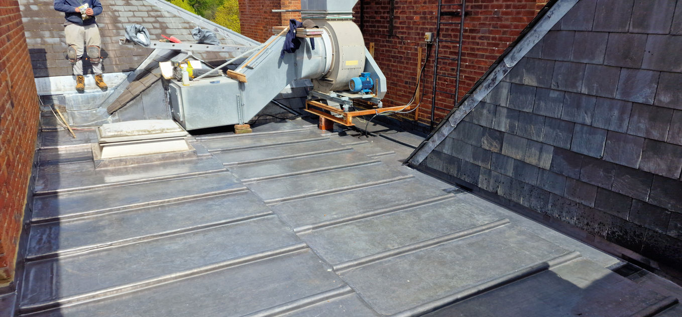 Roofer working on large lead flat roof