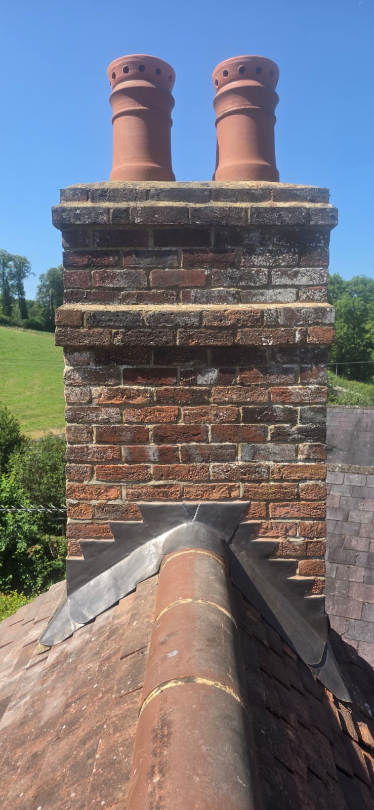 Rebuilt chimney with new lead back gutter and flashings, countryside behind